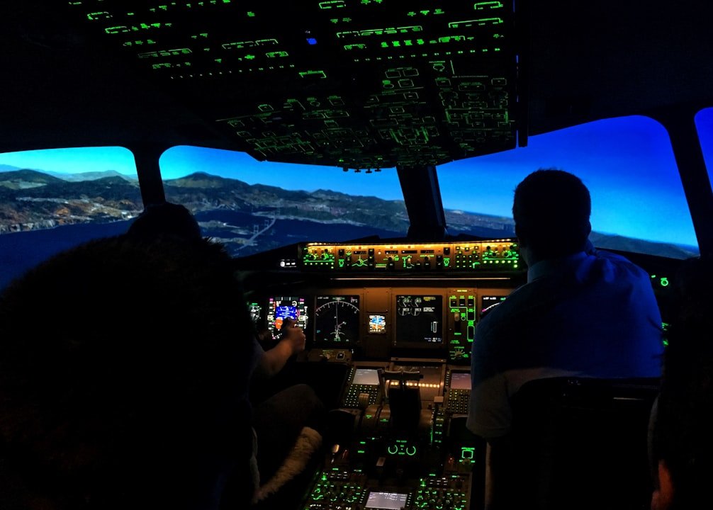 The interior of an airplane cockpit at night with illuminated control panels and screens displaying flight instruments.